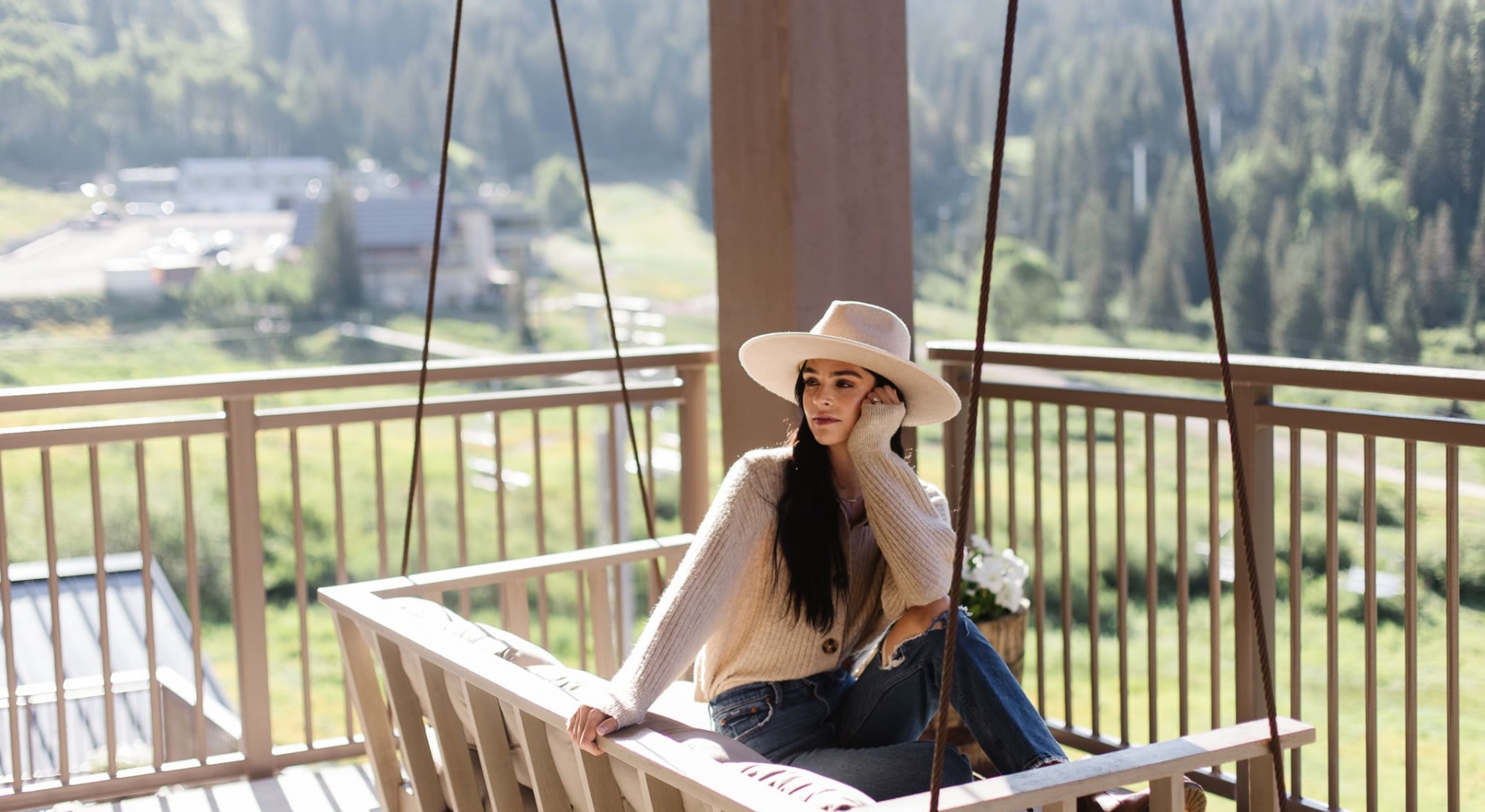 Woman sitting on a wooden swing on a oorch