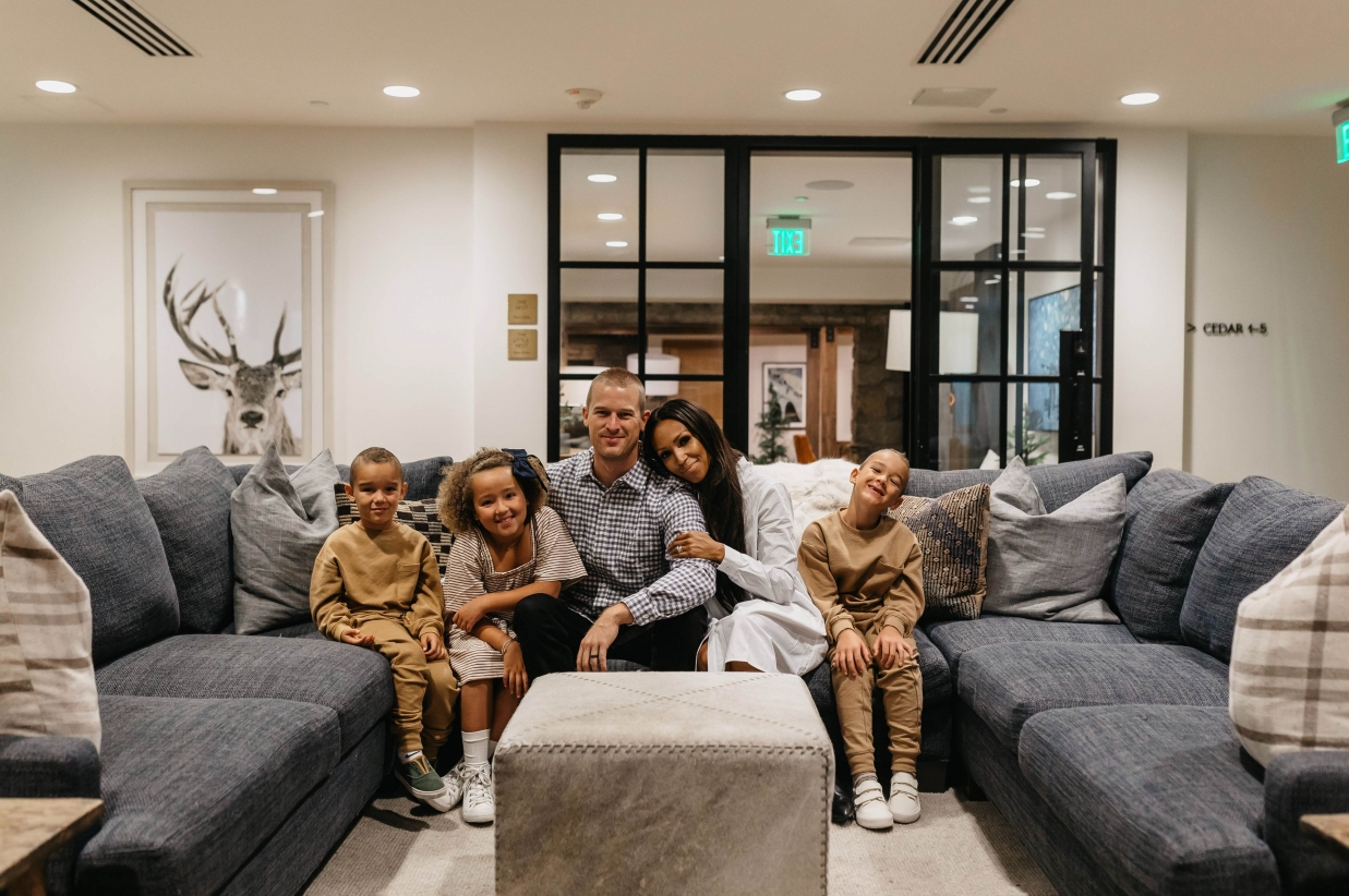 Father, mother, and three young kids sitting on a couch