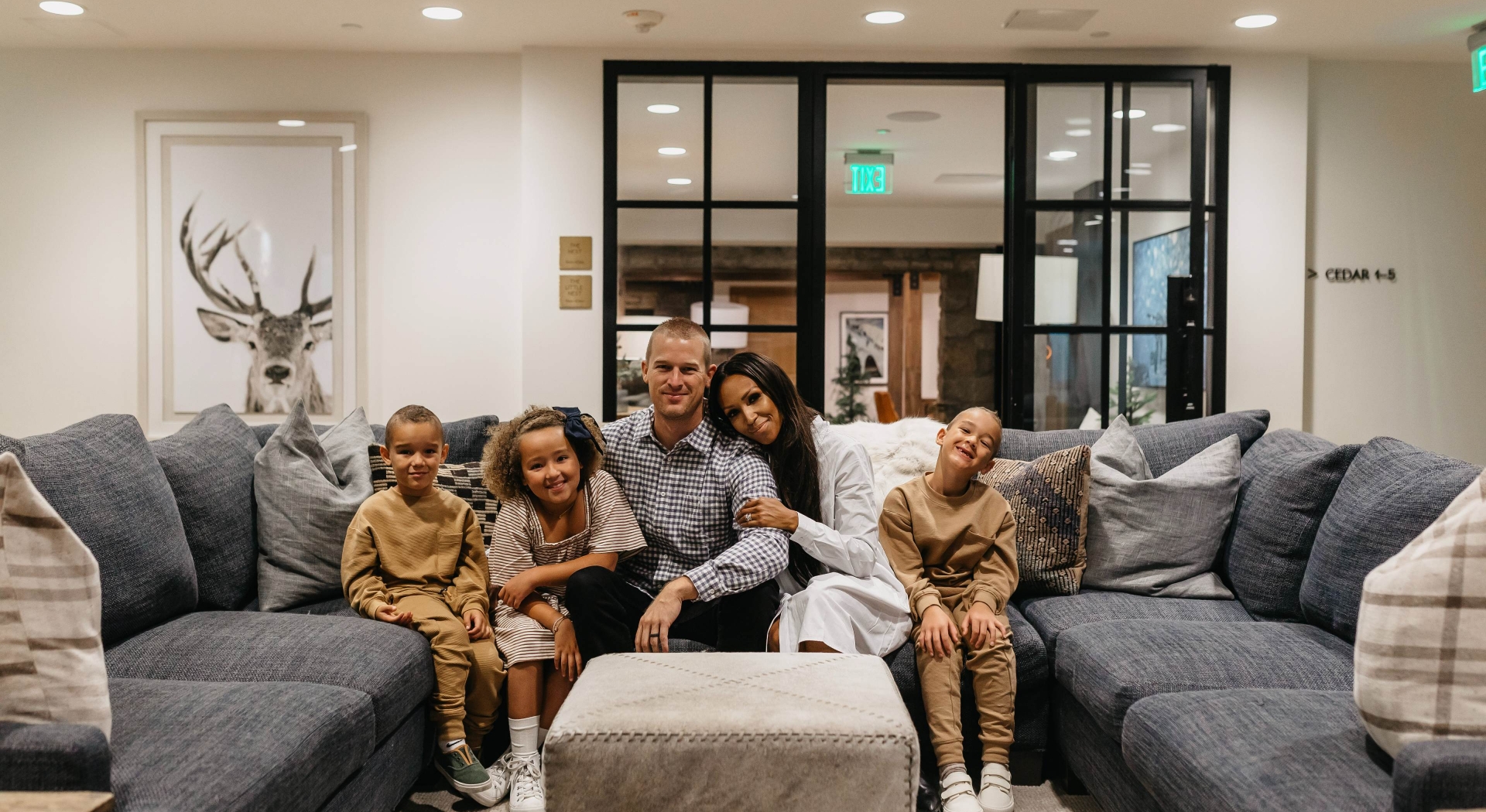 Father, mother, and three young kids sitting on a couch