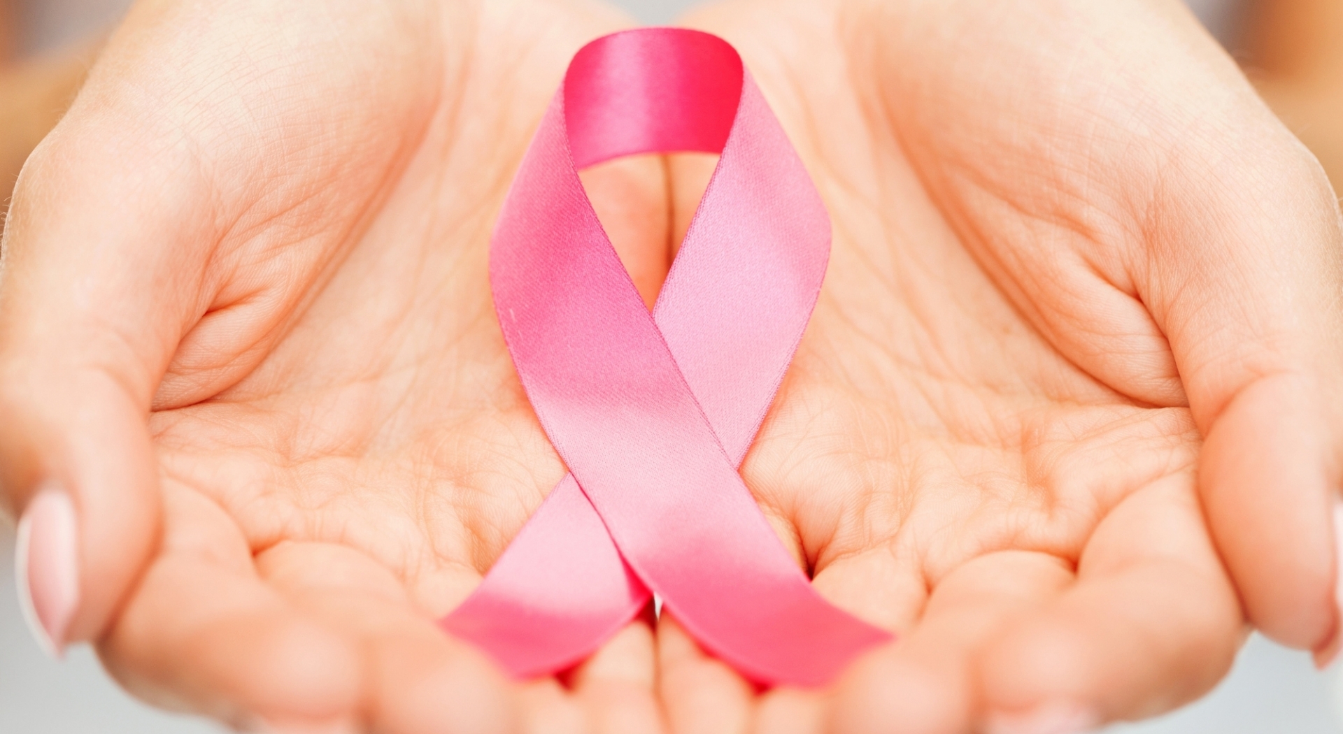 Hands holding a pink breast cancer ribbon