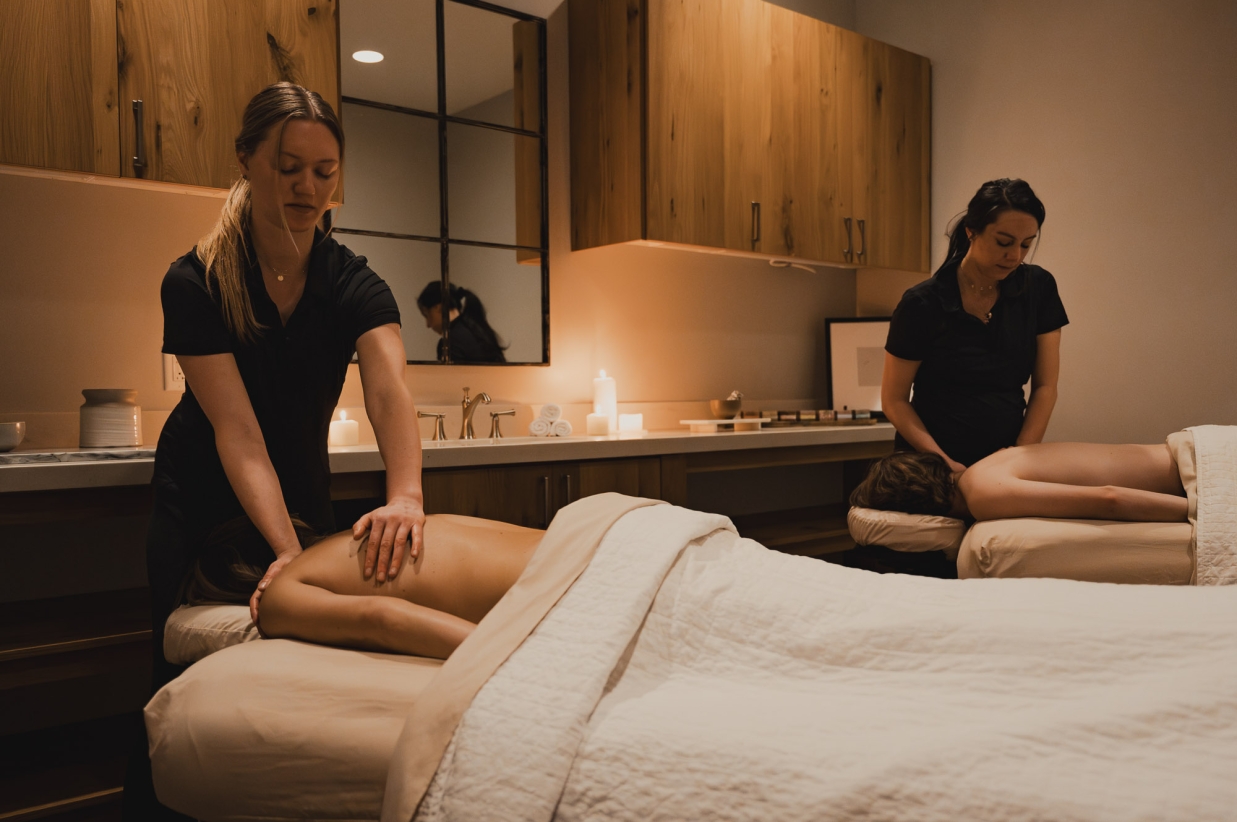 Two massage therapists performing treatments in a spa room.