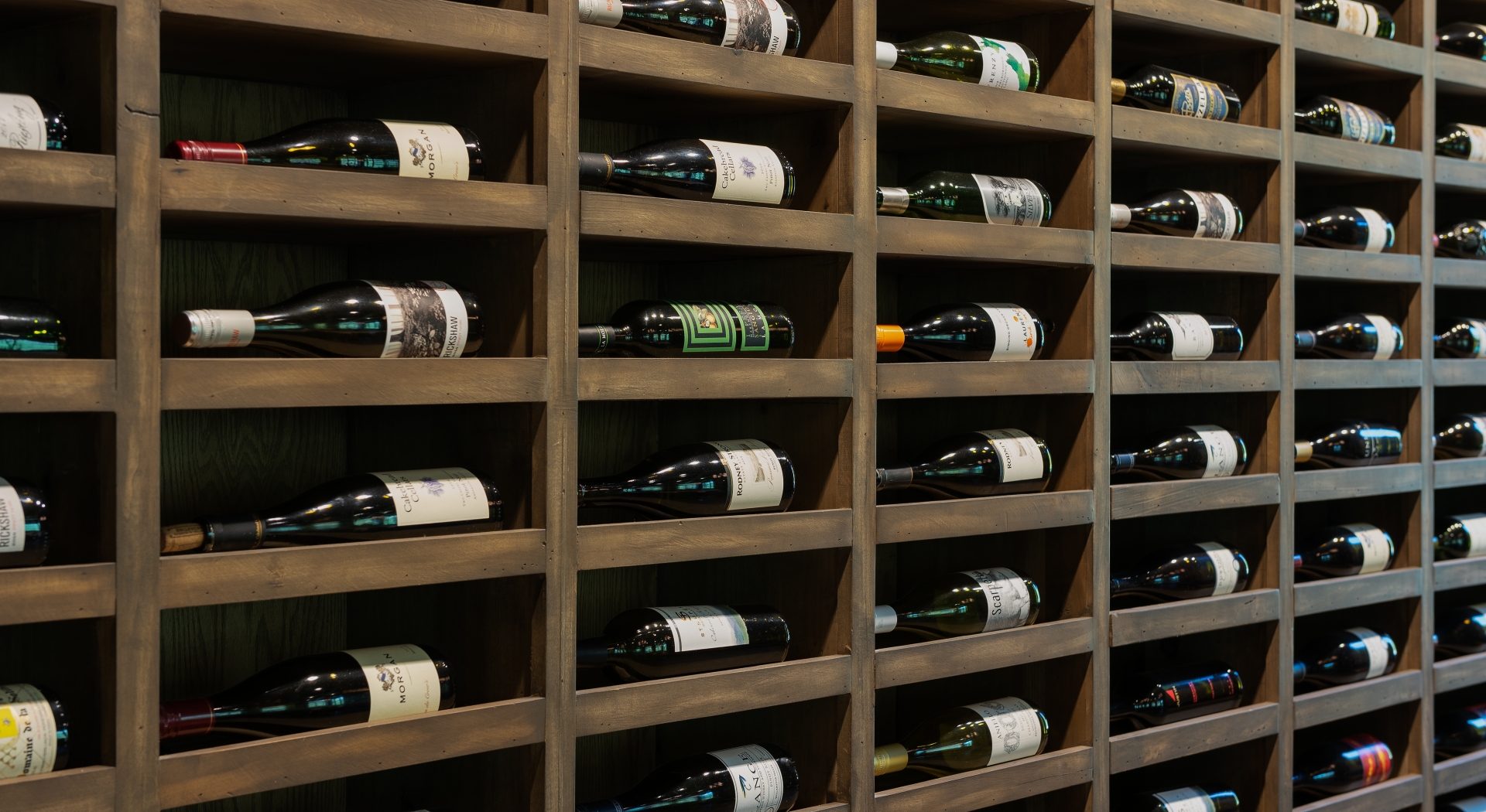 Wooden wine rack filled with bottles in a cellar.