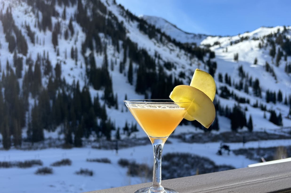 Yellow cocktail with a lemon garnish on a balcony railing.