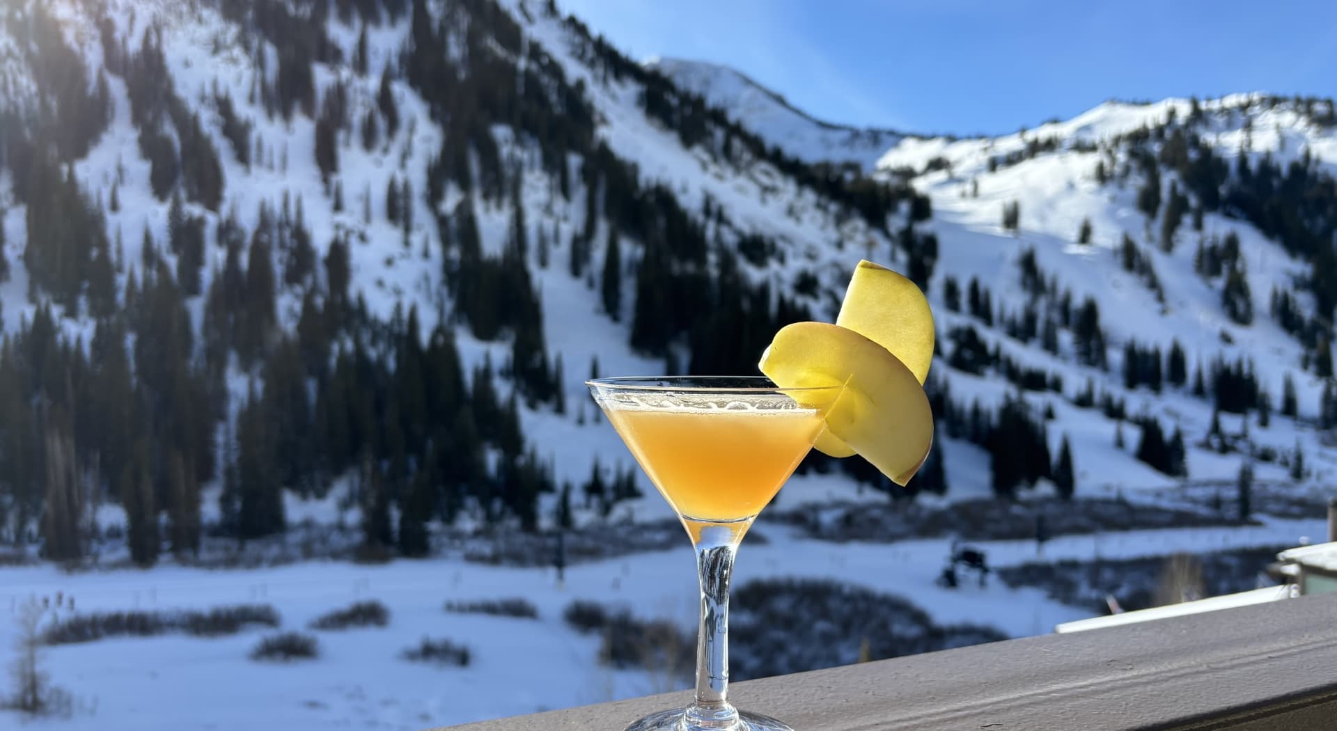 Yellow cocktail with a lemon garnish on a balcony railing.