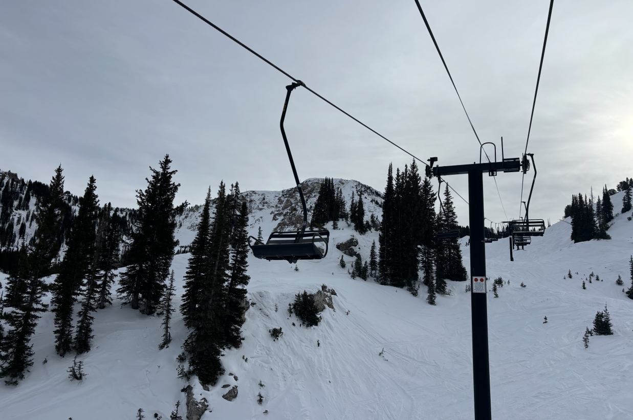 Looking up at ski lift cables and towers against a grey sky.