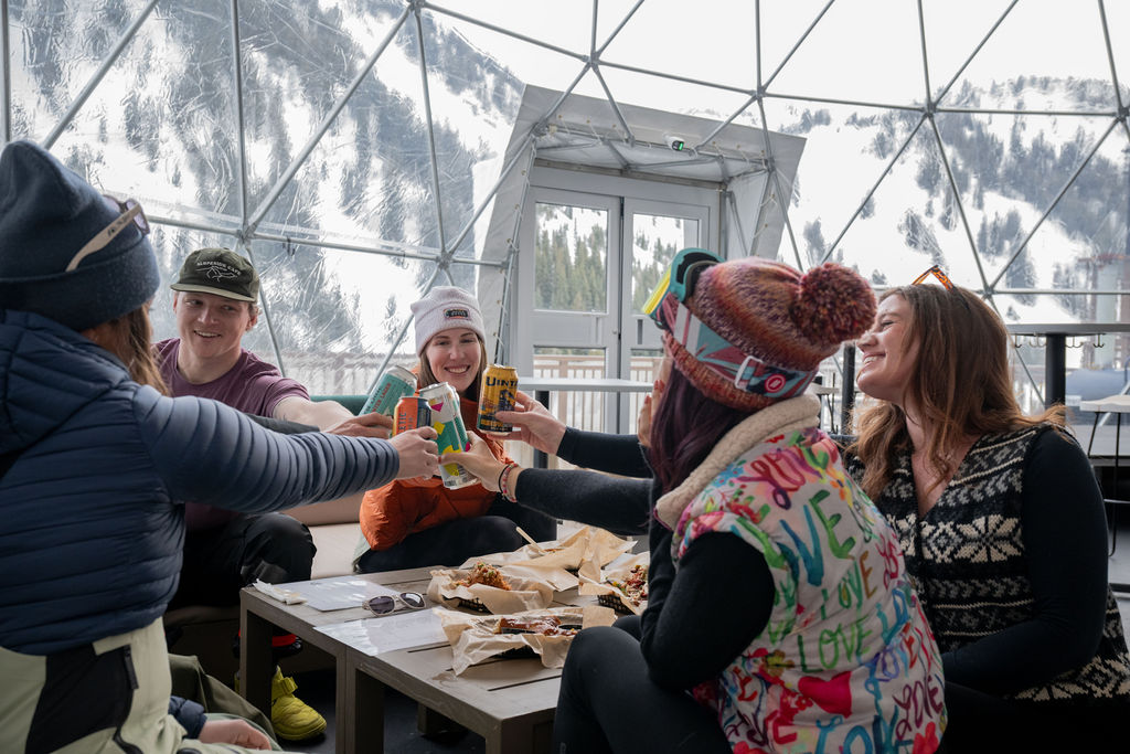 Group of friends toasting glasses at a table inside the dome.
