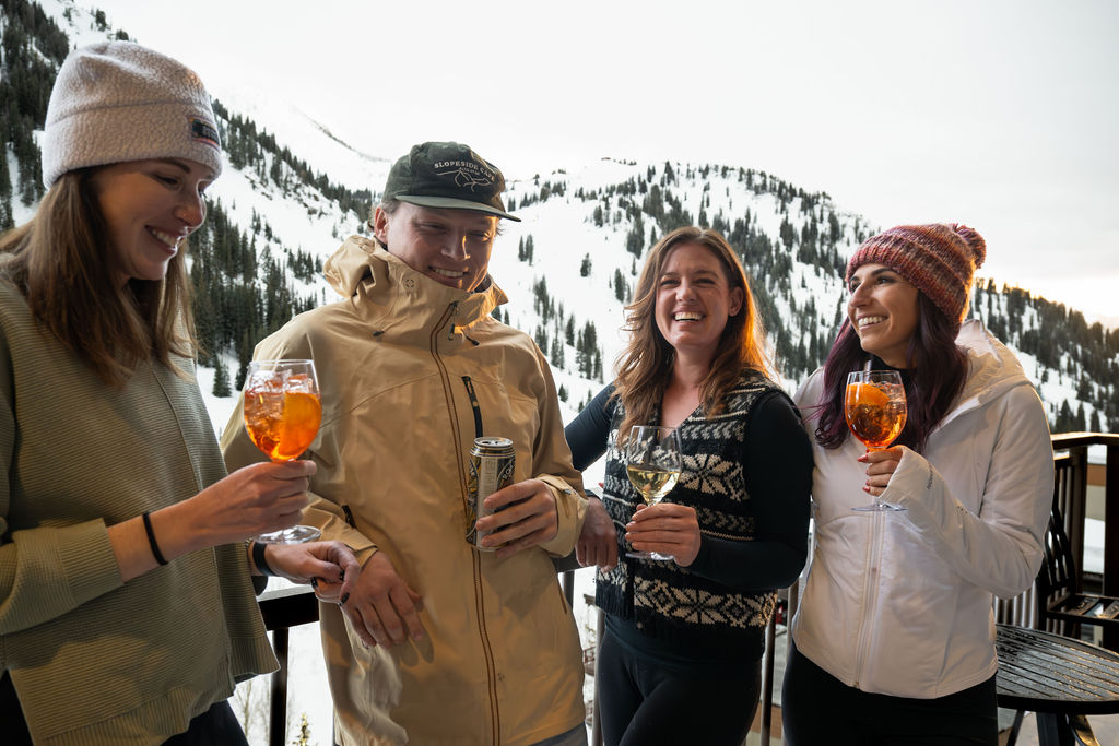 Group of four standing outside in winter gear holding cocktails.