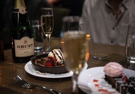 Close-up of champagne glasses and a chocolate dessert on a table.