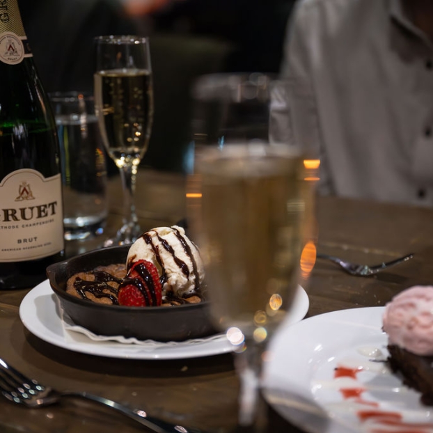 Close-up of champagne glasses and a chocolate dessert on a table.