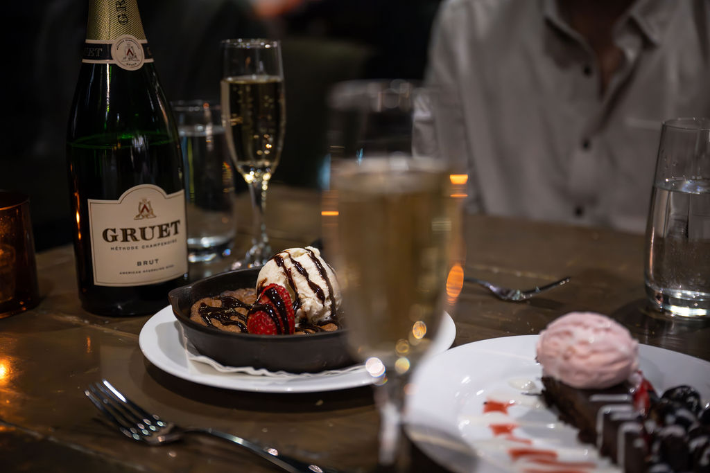 Close-up of champagne glasses and a chocolate dessert on a table.
