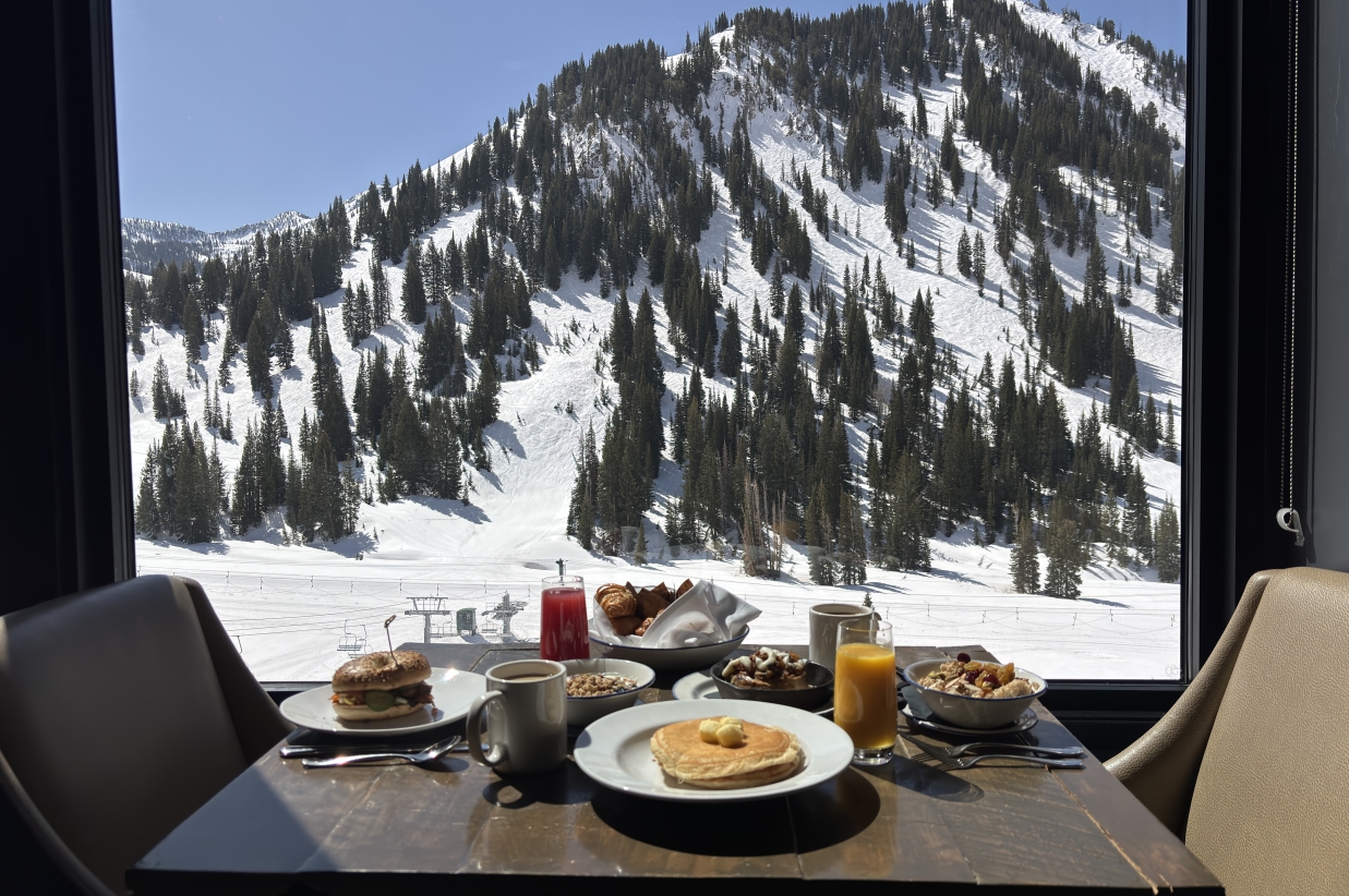Dining table set with food overlooking snowy mountains.