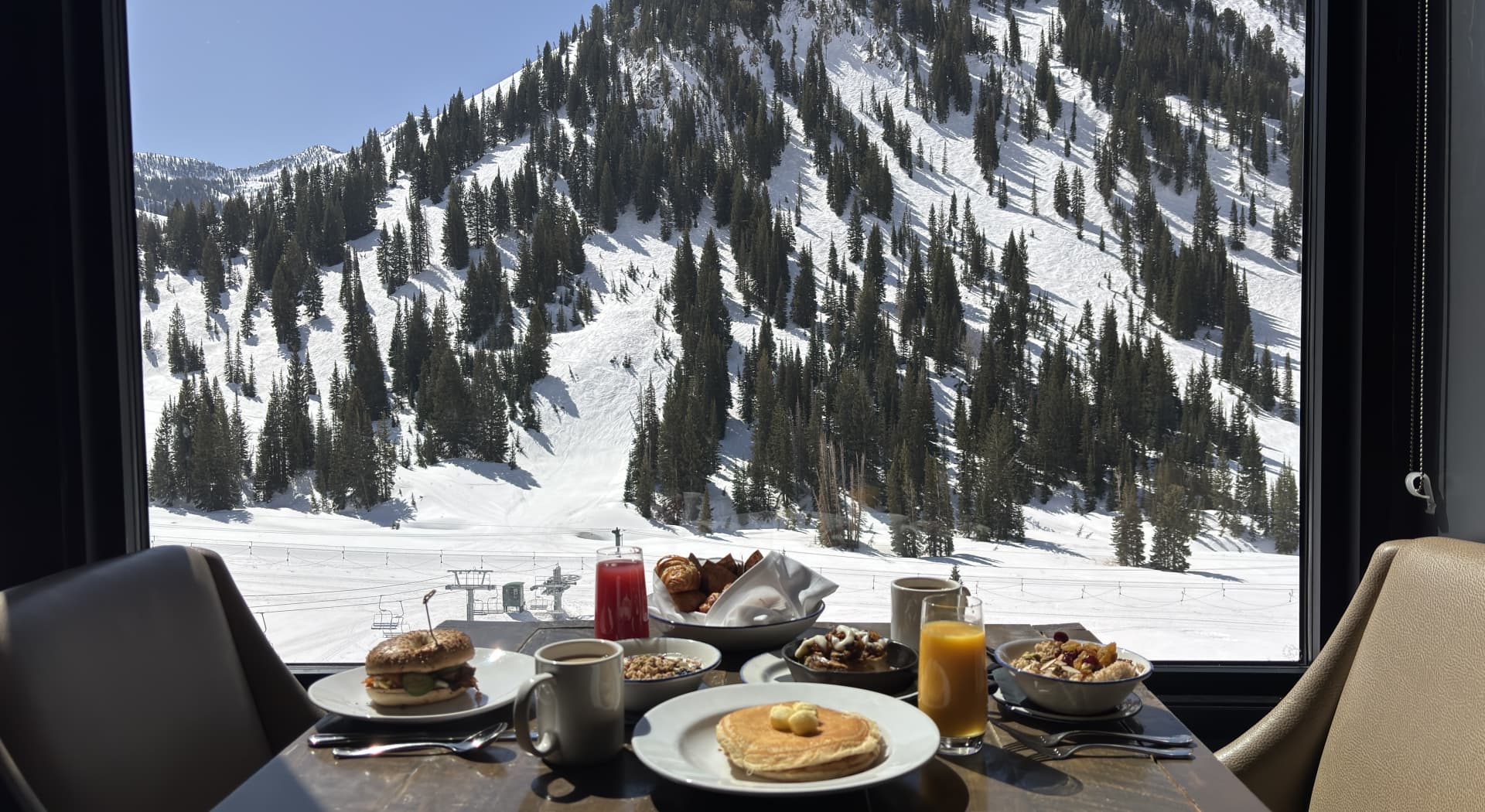 Dining table set with food overlooking snowy mountains.