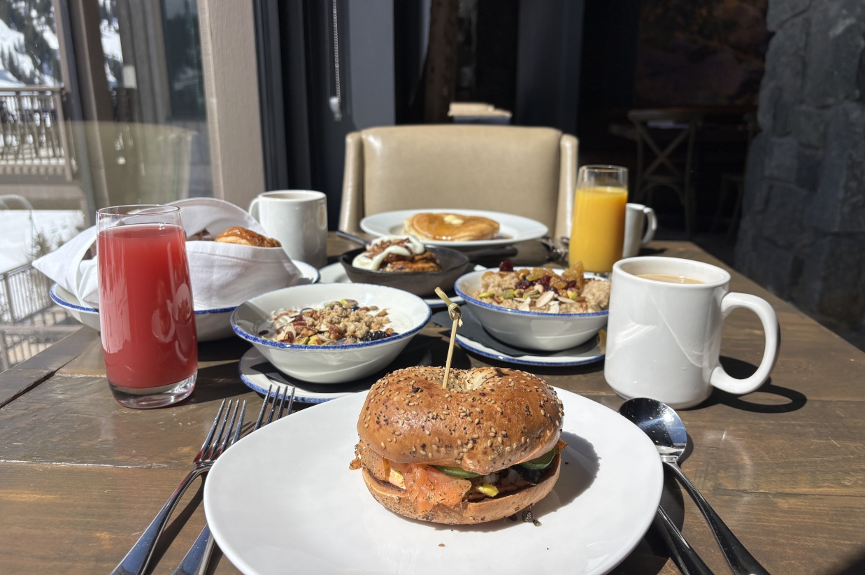 Breakfast bagel sandwich and coffee on a table near a window.