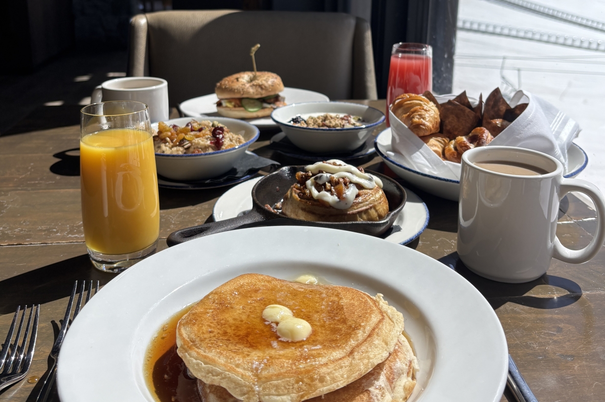 Close-up of a stack of pancakes with syrup and butter.