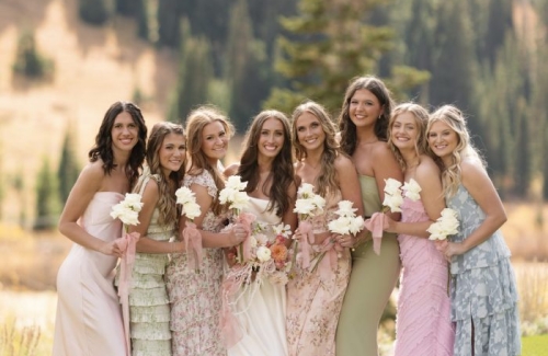 Bridesmaids in pastel dresses posing together with a mountain backdrop.