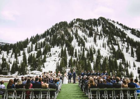 Outdoor wedding ceremony in snowy Alps, guests seated in rows facing the couple and bridal party.